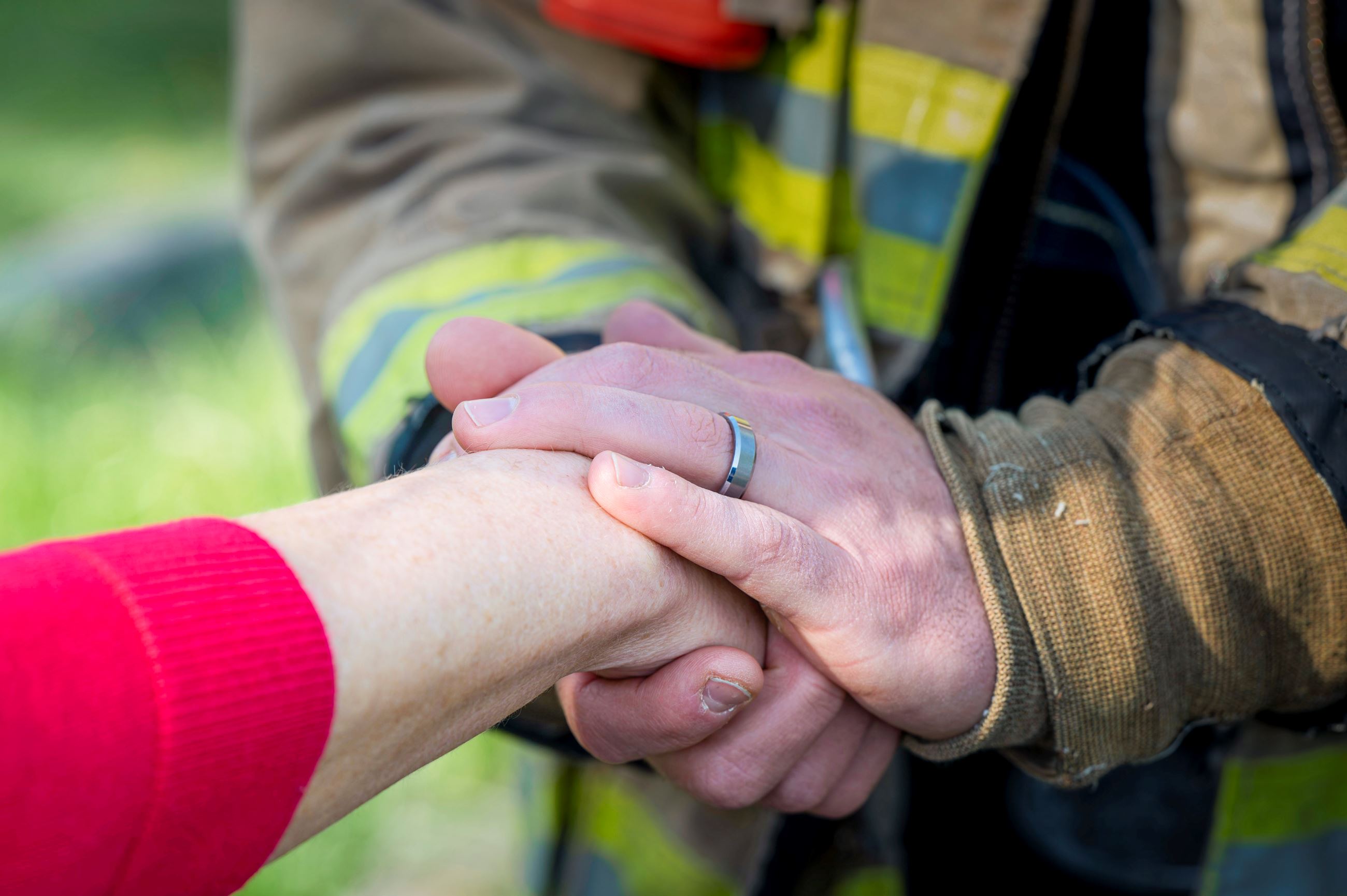 Firefighter hands hold hand of bystander offering comfort